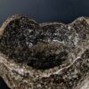 Raue Textur und helle Sandpunkte auf einer dunklen Wabi-Sabi Schale